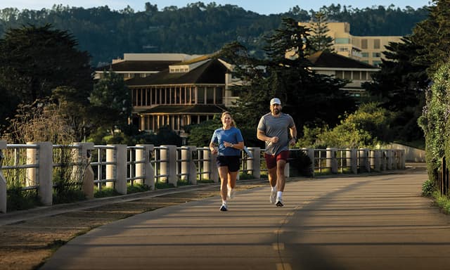Mann og kvinne med Garmin Forerunner 70 og 170-sportsklokker som løper over en bro.