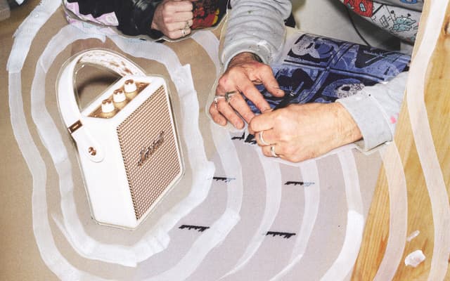 A beige Marshall Stockwell III speaker next to a man sitting on the floor.