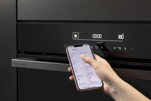 En person som bruker ConnectLife-appen på en smarttelefon til å styre Hisense-pizzaovnen.