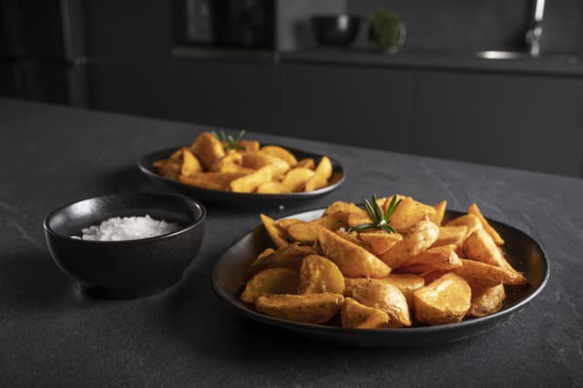 Sorte serveringsfat med luftstekte poteter tilberedt i en Hisense-pizzaovn.