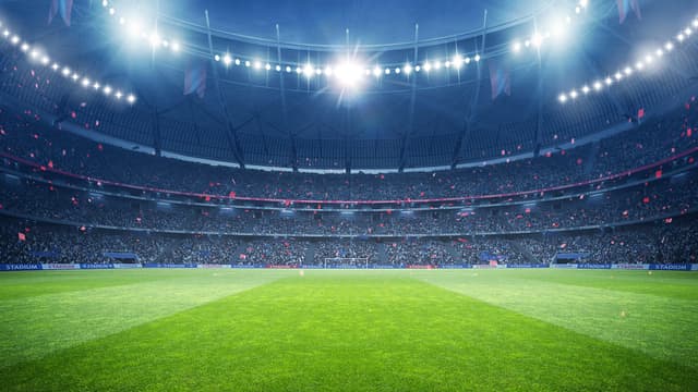 Et stadion om natten med stærke lys og pakkede tribuner