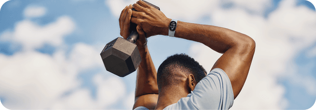 En mand træner med en håndvægt og et Fitbit Edge på håndleddet