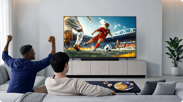 Two men watching a football match on a TV in a living room.