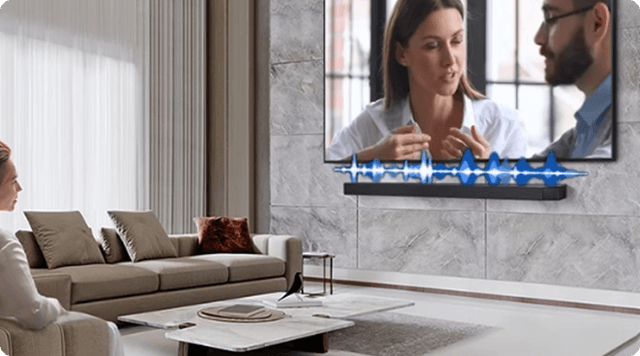 A woman sitting on a beige couch in a light living room watching a show on TV with a sound bar in front of it.