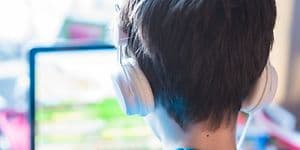 Dreng sidder foran gaming-laptop, mens han har hovedtelefoner på.