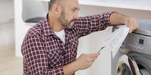 En mann sjekker instruksjonene når han installerer en vaskemaskin