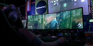 En gamer spiller et spill på en vid gaming-skjerm fra Elkjøp