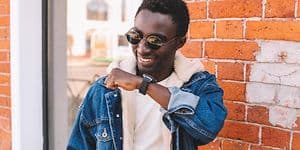 Mand der står med hånden oppe ved ansigtet og snakker ind i hans smartwatch