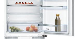 Litet kylskåp från Bosch med öppen dörr och några saker inuti som äpplen, en flaska och några små tillbehör. 