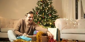 En man öppnar en julklapp som han fått av sin partner - Julklappar till pojkvän