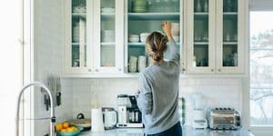 Kvinde sætter ting på plads i sine køkkenskabe