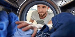 Mand der tager sit vasketøj ud af maskinen