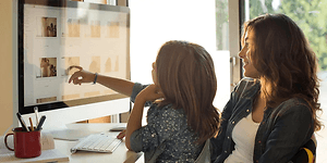 Mamma och dotter ser på bilder på en stor dataskärm.