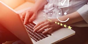 Lähikuva käsistä kirjoittamassa kannettavalla tietokoneella sekä kuvassa olevat luokitusmerkit