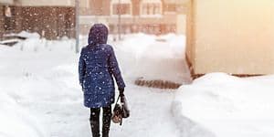 Uppvärmning: Kvinna som går genom stad när det snöar om vintern.