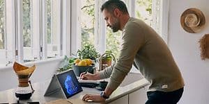 Keittiösaarekeella työskentelevä mies sekä taitettuna oleva HP EliteBook