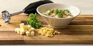 En sort stavblender ved siden af ingredienser og en skål