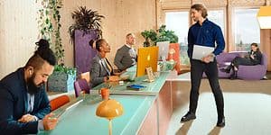 Kontor med ansatte som bruker Apple-produkter og en mannlig elkjøp-ansatt