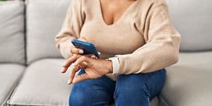 Telecom - Wearables - woman wearing a smartwatch with a smartphone in her hand