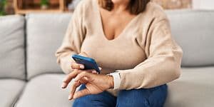 Telecom - Wearables - woman wearing a smartwatch with a smartphone in her hand