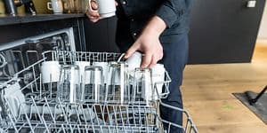 Mann som tømmer en oppvaskmaskin på jobb
