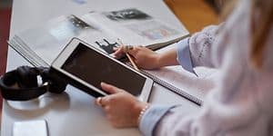 Kvinne som holder nettrett i sin hånd men hun jobber med studiene sine