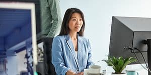 Kvinde, der sidder foran en arbejdscomputer på et kontor