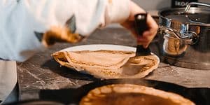 En stegepande med gyldne pandekager tilberedt på en induktionskogeplade, jævnt opvarmet på det moderne komfur