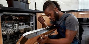 Man using screw driver on dishwasher