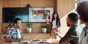 Nainen esittelee sisältöä kokoushuoneessa olevasta TV:stä