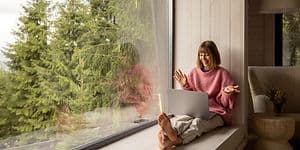 Internet i sommerhus: Kvinde sidder med laptop i vindue i sommerhus