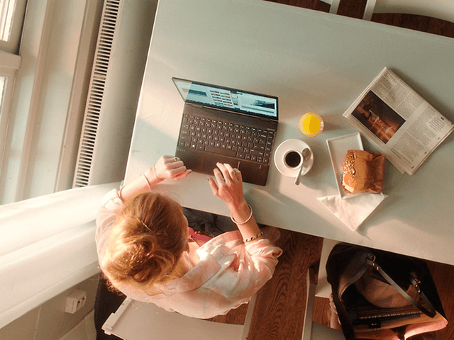 Kvinde der skriver på HP computer mens hun spiser frokost