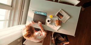 Kvinde der skriver på HP computer mens hun spiser frokost
