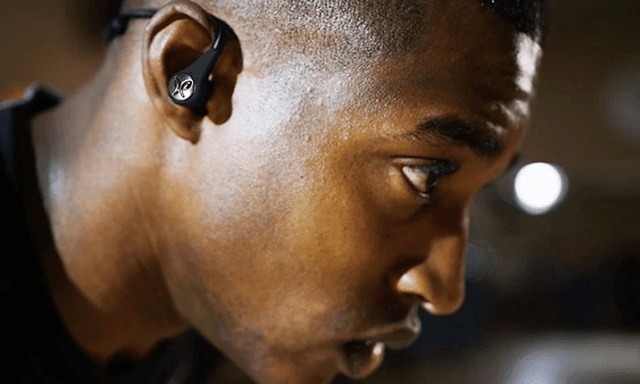 Mies työskentelemässä in-ear-kuulokkeet korvillaan