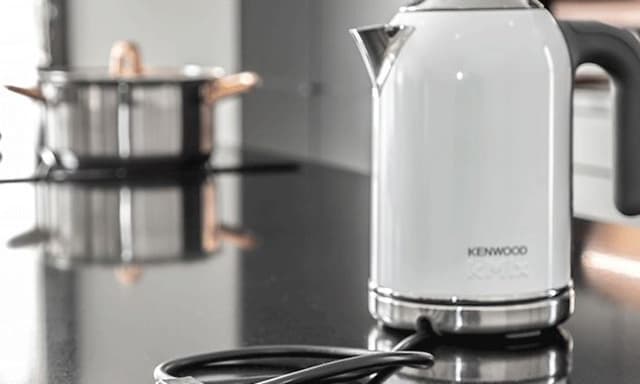 Köksö med en kastrull på en integrerad spishäll och en vit vattenkokare i snygg design som passar in i stilen.