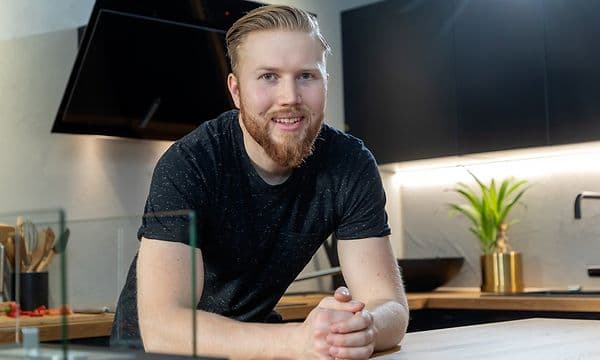 mann smiler på epoq-kjøkken med detaljer i sort og tre