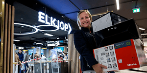 Kvinde med favnen fuld af varer forlader Elkjøp mjed et smil på læben