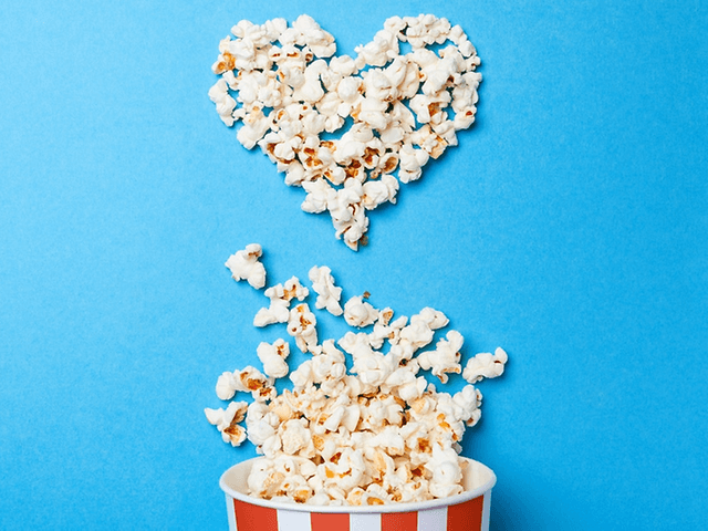 popcorn i bøtte og popcorn mot blå bakgrunn i en hjerteform