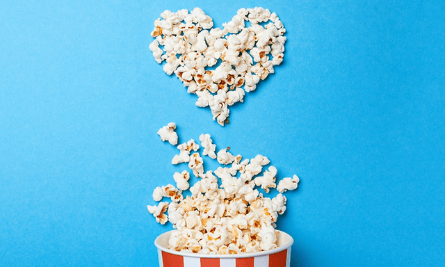 popcorn i bøtte og popcorn mot blå bakgrunn i en hjerteform