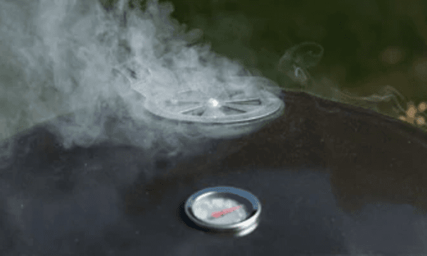 Hiiligrillin kansi, jonka tuuletusaukosta tulee savua