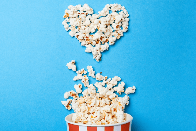 Popcornit aseteltu sydämen muotoon sinistä pöytää vasten