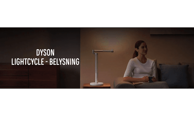 Dyson Lightcycle banner med kvinna som sitter i en soffa med sidobord och en bordslampa bredvid. 