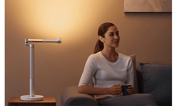 Kvinne som sitter ved Dyson Lightcycle Morph skrivebordslampe
