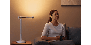 Kvinde sidder ved siden af Dyson Lightcycle Morph bordlampe