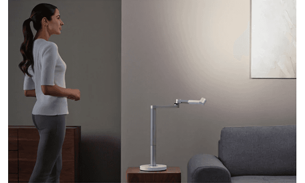 Nainen seisoo Dyson Lightcycle Morph -pöytävalaisimen vieressä