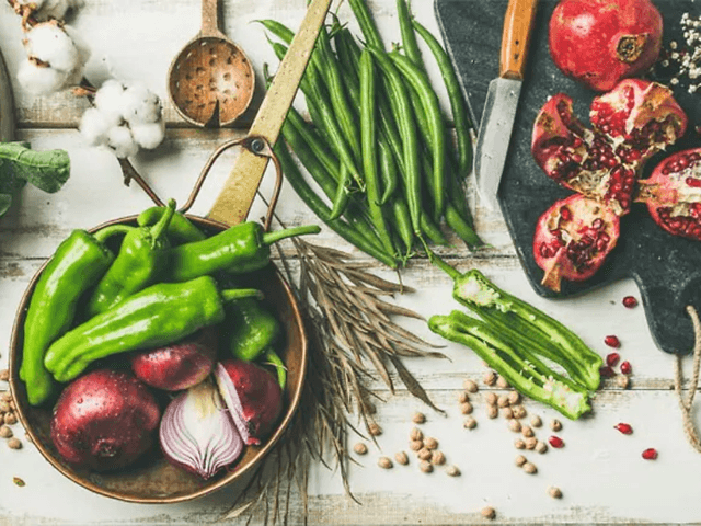 Flatlay foto av grönsaker, frukt och kryddor på ett bord.