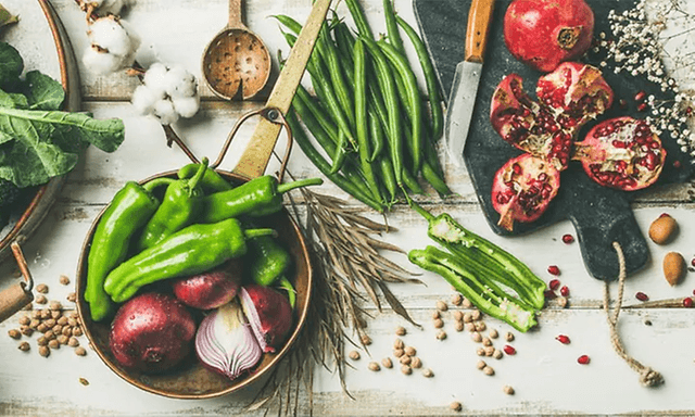 Flatlay foto av grönsaker, frukt och kryddor på ett bord.