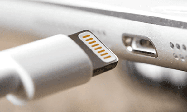 En vit sladd med lightning-anslutning och en port som den är på väg att anslutas till. Används till Apple-produkter. 