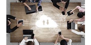 Syv personer omkring et bord arbejder sammen via cloud-lagring