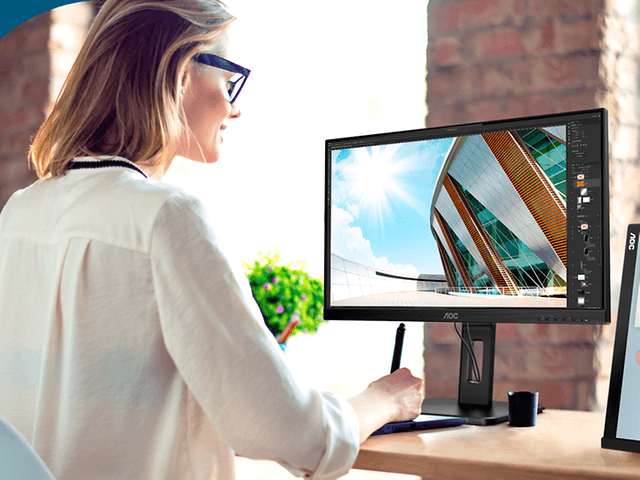 Kvinna som sitter vid ett skrivbord och arbetar med en AOC-skärm